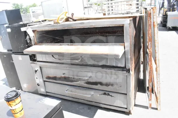 Bakers Pride commercial gas pizza oven, single deck, used condition with visible rust and wear, includes labeling.