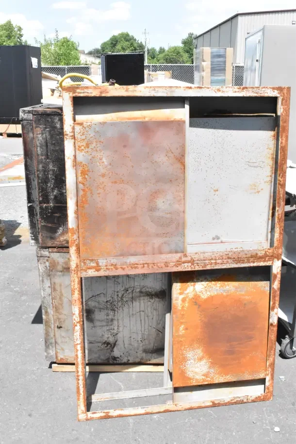 Two Bakers Pride commercial gas-powered single deck pizza ovens, heavily rusted and outdoor visible.