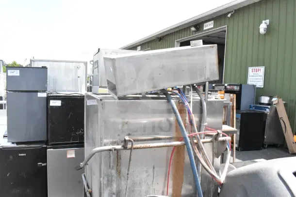 CMA AH-2 Commercial Straight Pass Through Dishwasher; visible wear, multiple hoses attached, located outside alongside other equipment.