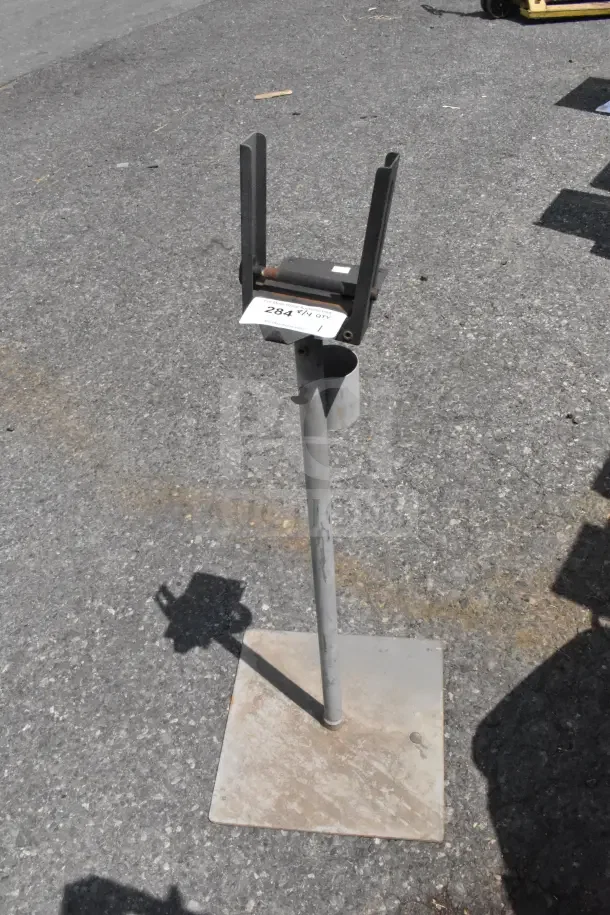 Metal stand with U-bracket on concrete surface, showing wear and rust. Includes label "Lot 284" indicating auction details.