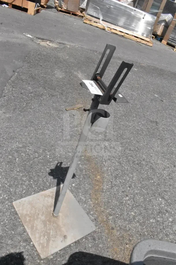 Tall metal stand with adjustable brackets, mounted on a square base. Visible label reads "2067." Weathered condition.