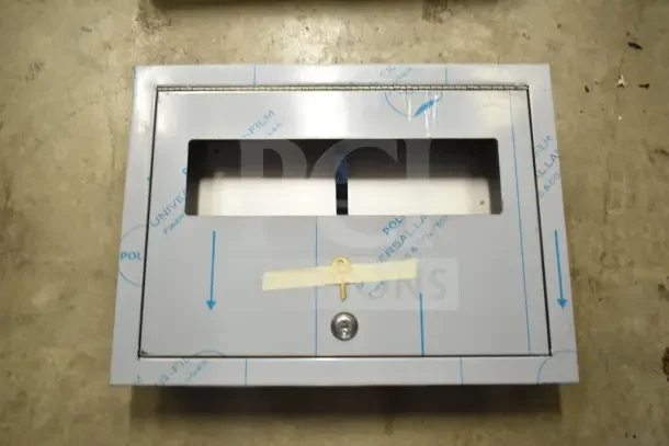 Toilet seat cover dispenser, metal construction, protective film, lock with key taped to front, new condition.