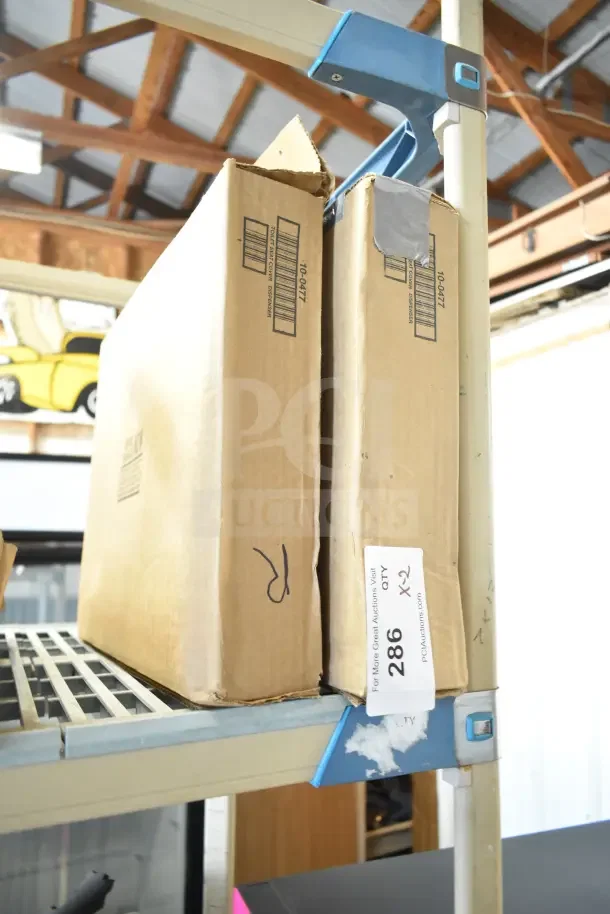 Two cardboard boxes containing various items, including a toilet seat cover dispenser, labeled with auction lot number 286.