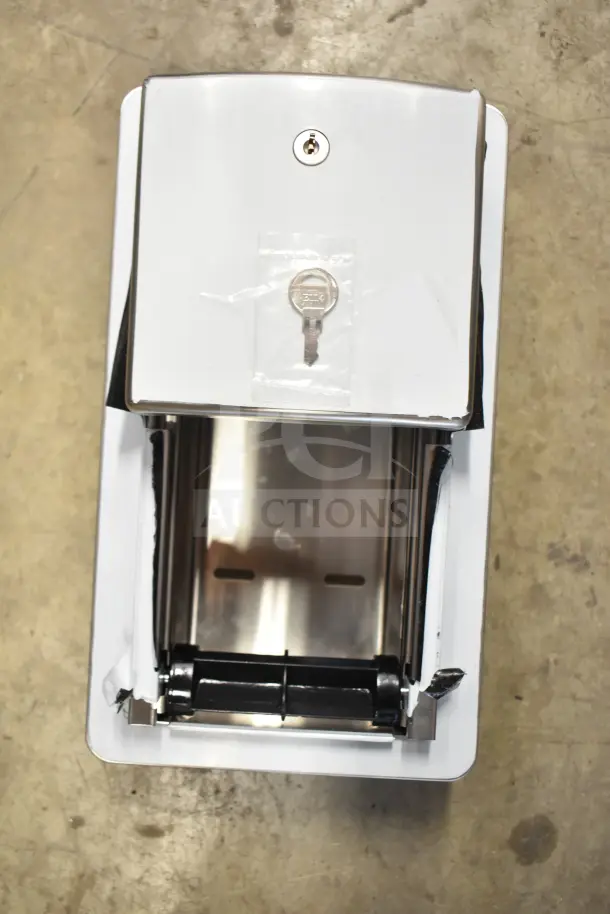 Stainless steel toilet paper dispenser with key lock, minor exterior wear, and protective packaging, suitable for commercial use.