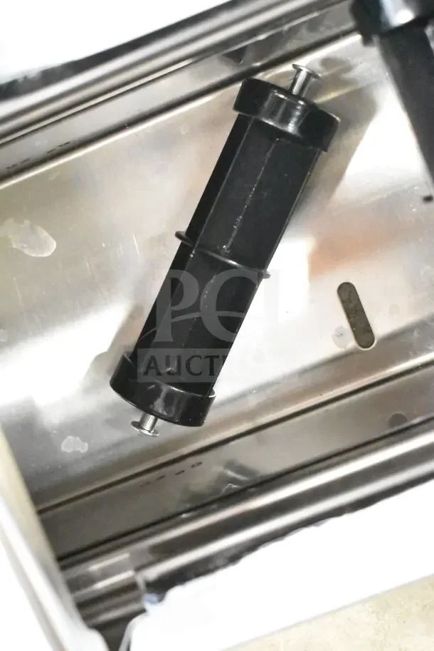 Stainless steel toilet paper dispenser with a black spindle, showing minor wear, ideal for commercial use.