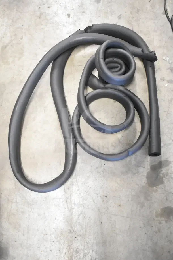 Coiled black hoses on concrete floor, new condition. Part of an auction lot of 18 items including thermometers and hoses.