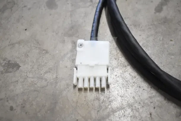 White multi-pin connector with black cable on a concrete surface. Part of 18 new boxed items including thermometers and hoses.