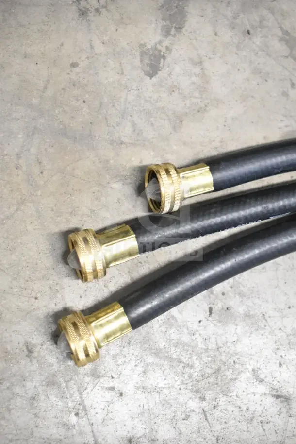 Three new black hoses with brass connectors and mesh filters, part of 18-item auction package, on concrete floor.