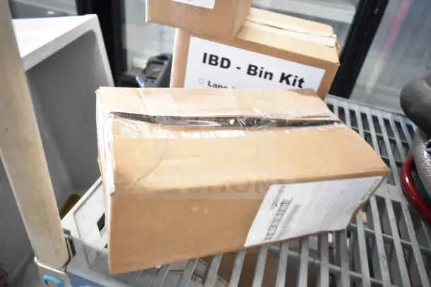 Four boxes including soap dispenser, rack, and IBD Bin Kit, all brand new, taped and labeled, stacked on a shelf.