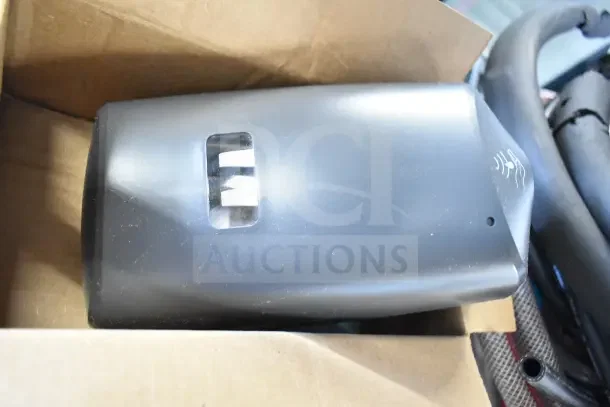 Brand new black soap dispenser partially visible in a box, with symbol indicating motion sensor activation.