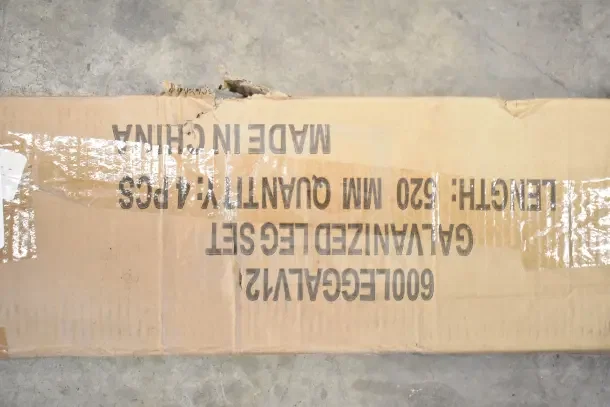 A damaged cardboard box labeled "Galvanized Leg Set, Length: 520mm, Quantity: 4pcs, Made in China."