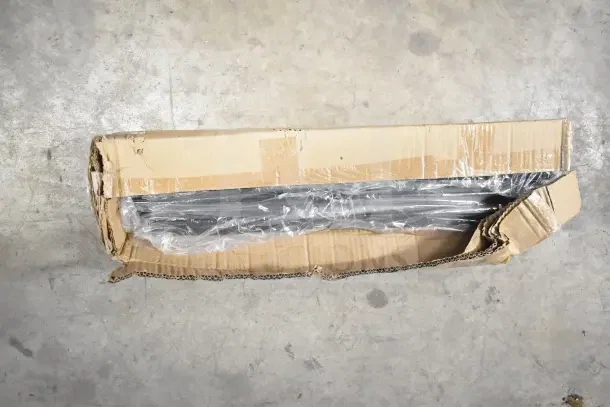 Cardboard box containing adjustable shelving brackets and legs, partially opened, in fair condition.