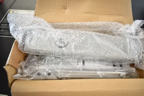 New Falcon SC81A door closer in box, wrapped in bubble wrap, with hardware accessories visible.