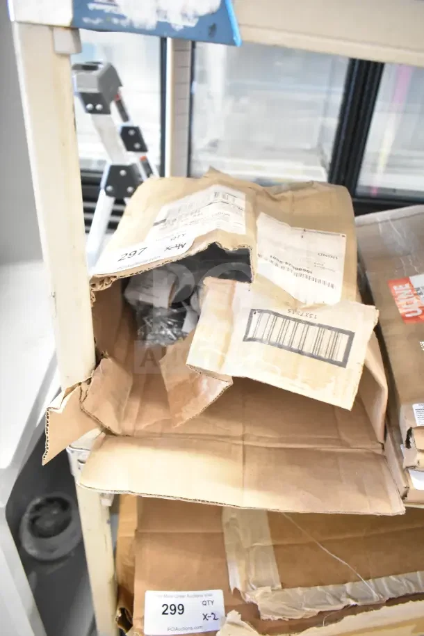 Cardboard boxes labeled "299 QTY X-2" contain brand new items, including hinges, on a metal shelf.