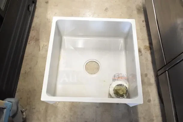 Brand new Poly Mop Sink in box, pristine condition, includes installation materials, square white design with center drain.