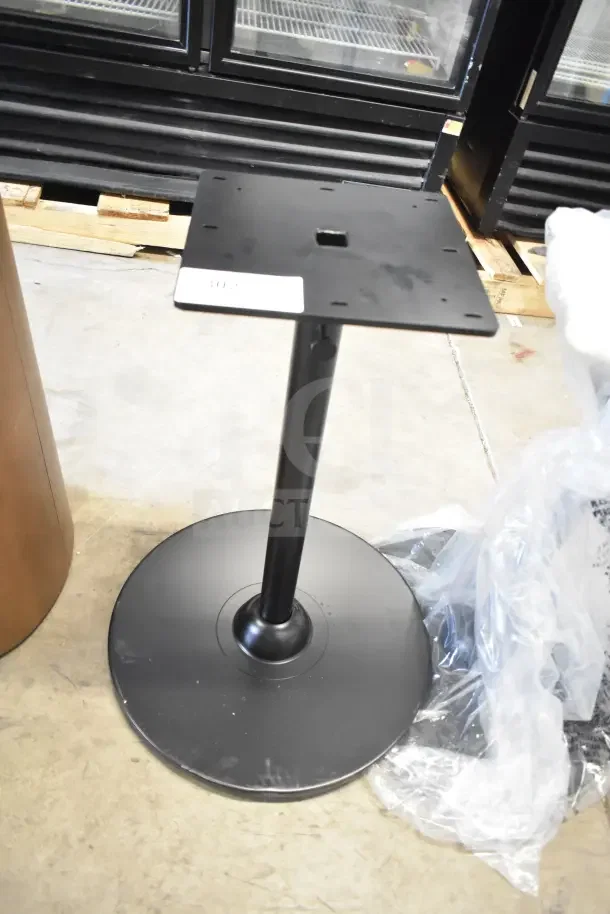 Two black metal stands with round bases. New condition. Ideal for displays or tables. Includes auction tag.