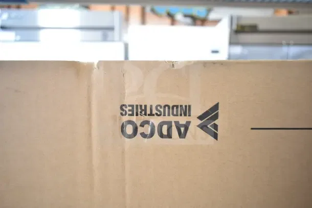 Cardboard box labeled "ADCO INDUSTRIES," containing a scratch and dent 18" Stow Away Utility Cart.