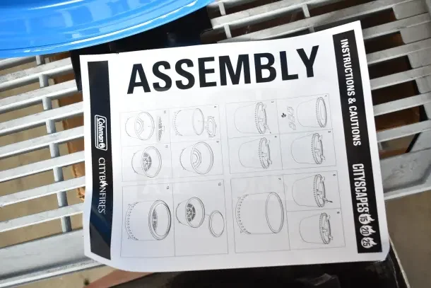 Brand new Coleman smokeless fire pit assembly instructions on a grille. Includes detailed diagrams and warnings.
