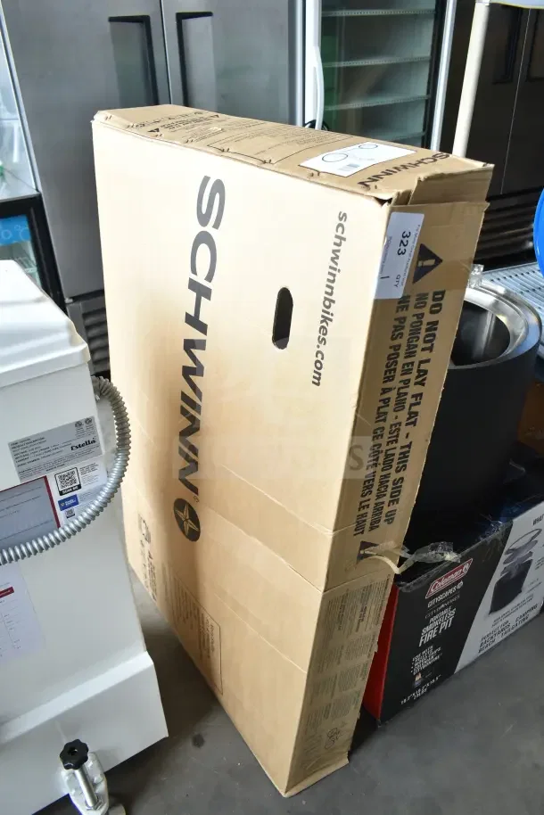 Brand new Schwinn Shuffle 26" adult scooter in a box, labeled with "Do not lay flat," indicating fragile handling. White model.
