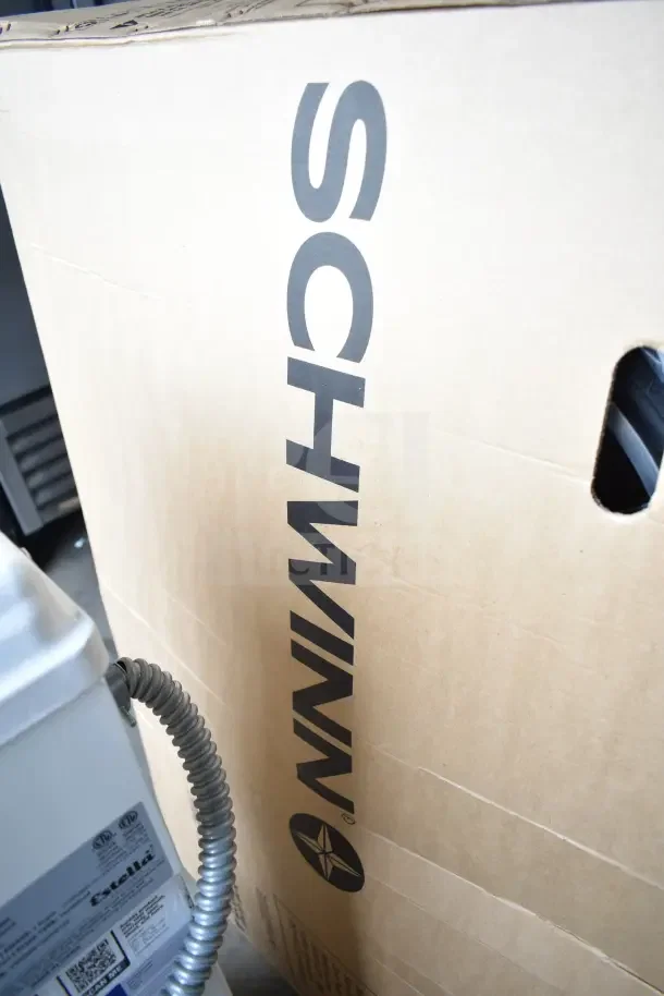 Cardboard box with "SCHWINN" logo, indicating a brand new Schwinn Shuffle 26" adult scooter, white, with minor scratches.