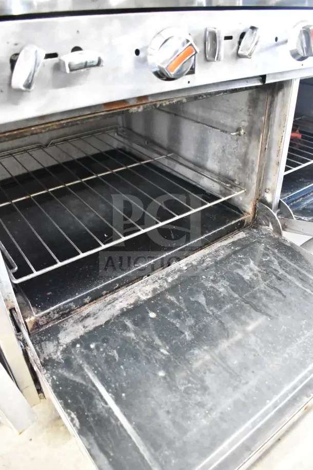 Commercial gas-powered range with 4 burners, flat top griddle, 2 ovens, and backsplash; shows interior and control knobs.