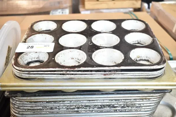 Stack of aged muffin baking pans, showing wear, includes visible auction tag, labeled "28 QTY."
