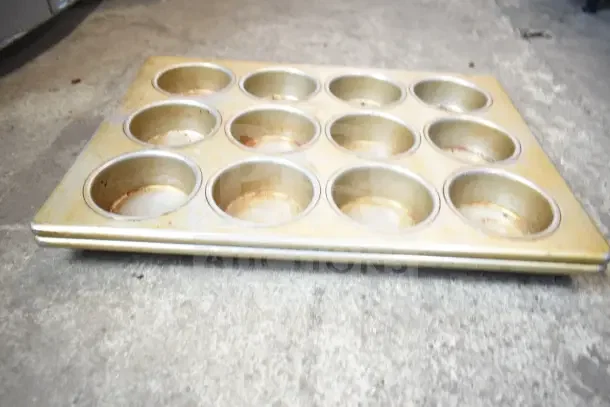 Tarnished metal muffin baking pan with 12 cups, used condition. Part of a lot of 40 various auction items.