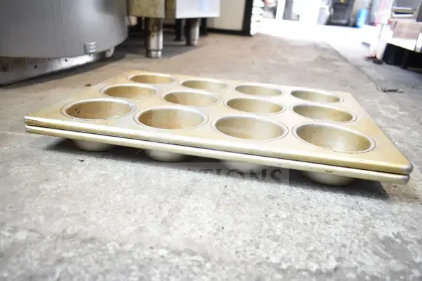 Two stacked muffin baking pans, each with 12 cups, showing signs of wear. Auction lot includes 40 items.