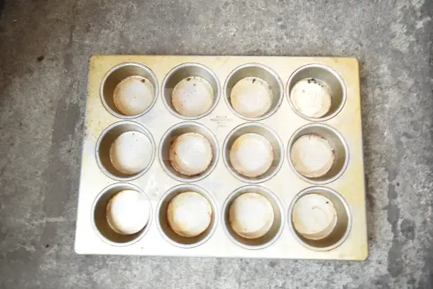 Muffin baking pan with 12 cups in used condition, showing signs of wear. Includes various other items, total of 40 pieces.