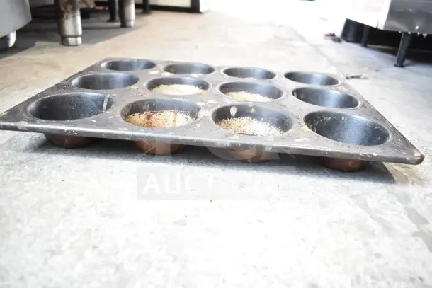 Metal muffin baking pan with 12 cups, shows signs of use, offers versatile baking options, part of 40-item auction lot.