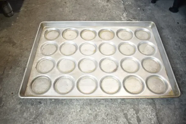 Aluminum muffin baking pan, 24-cup, slightly used. Part of 40-item auction lot. No visible brand or markings.