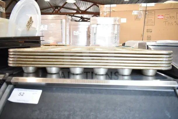 Stack of muffin baking pans in used condition, part of a lot with 40 various items. Tag shows auction lot number 52.