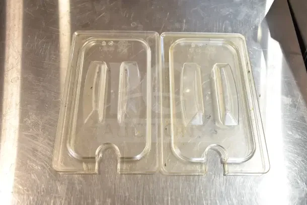 Clear plastic trays with raised sections, placed on a stainless steel surface. Visible labels indicate recyclability.