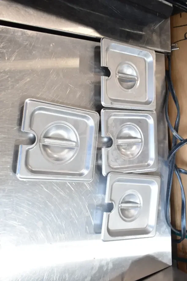 Four stainless steel square lids with handles on a metallic surface. Part of a set of 40 baking items.
