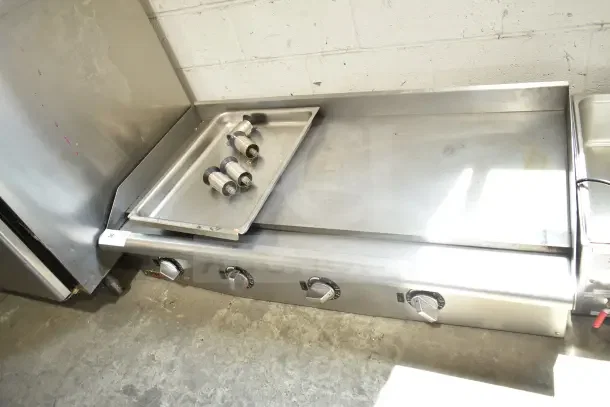 APW Wyott Commercial Countertop Flat Top Griddle with adjustable knobs, stainless steel, in used condition, includes drip tray.