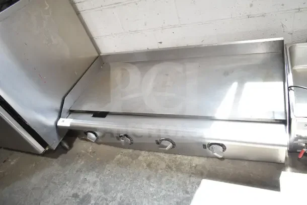 APW Wyott commercial countertop flat top griddle, stainless steel, with three control knobs, in used condition.