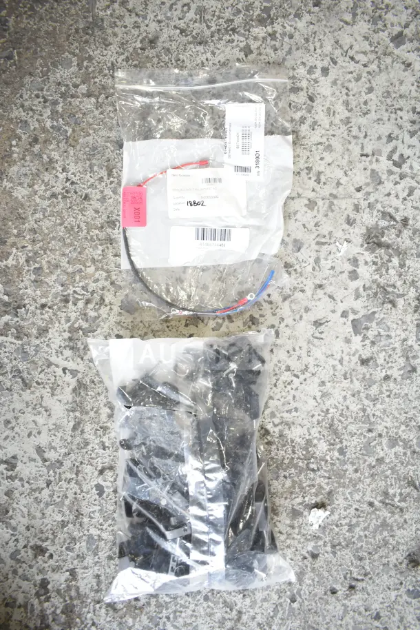 Assorted new scratch and dent items in sealed bags, including a millivolt harness with label and barcodes visible.