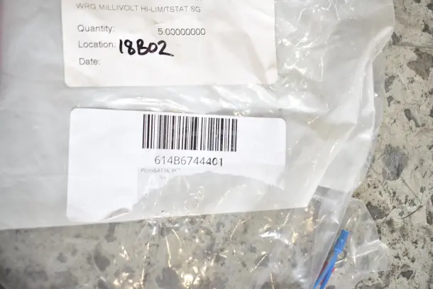 Clear plastic bag with barcode 614B6744401, marked "WRG MILLIVOLT HI-LIM/TSTAT SG," containing assorted new scratch and dent items.