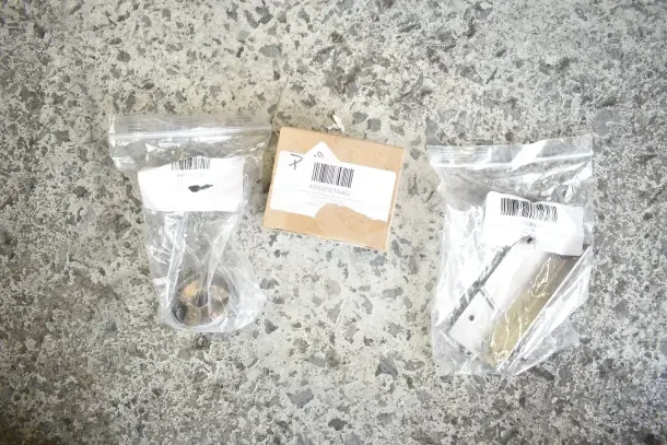 Assorted new scratch and dent items including gasket, harness, bracket, knob, and caster in packaging with labels.