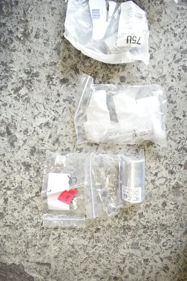Various new scratch and dent items in packaging including gasket, millivolt harness, mounting bracket, knob, and caster.