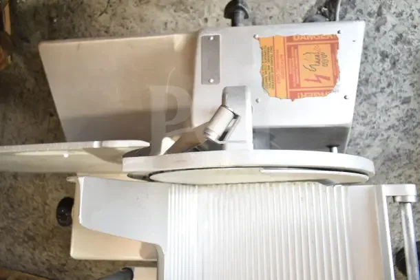 Bizerba commercial countertop meat slicer, 120 volts, 1 phase, sturdy metal construction, visible safety warning label.