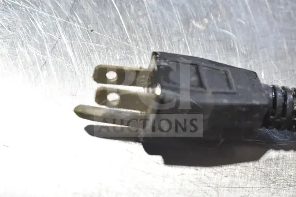 A close-up of a black power plug against a metallic surface.
