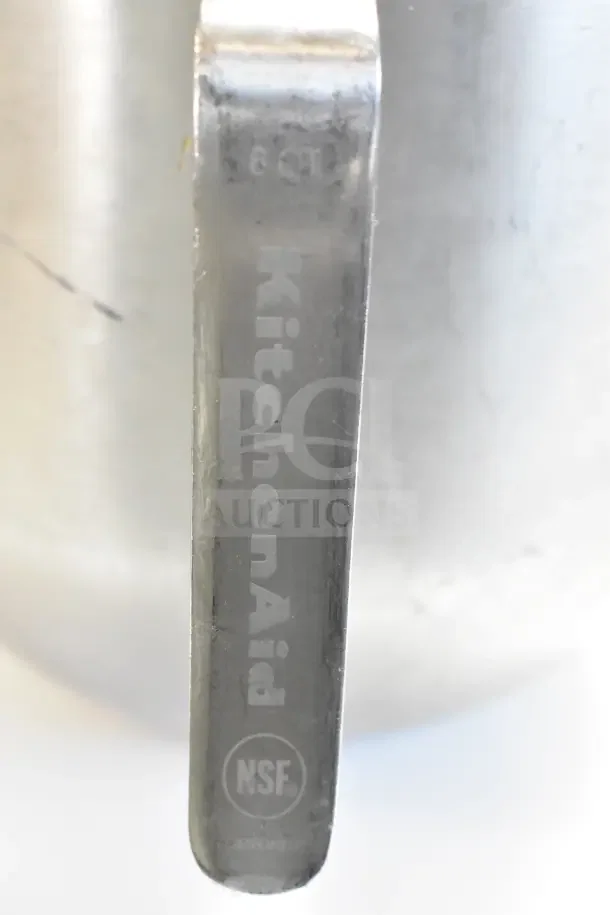 Handle of a KitchenAid stock pot, showing NSF component marking and "8 QT" stamp. Stainless steel, commercial grade.