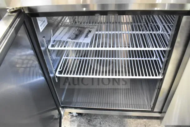 BRAND NEW Migali Commercial Pizza Prep Table, 115 Volts, 1 Phase, scratch and dent condition, open door showing shelves.
