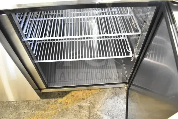 Migali commercial pizza prep table, brand new with minor scratches, 115 volts, 1 phase, stainless steel, open door showing shelves.