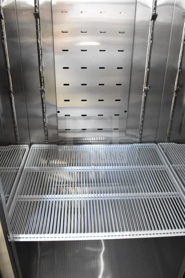 Brand new Migali C-3RB-HC commercial 3-door reach-in cooler interior. Features stainless steel shelves and adjustable racks.